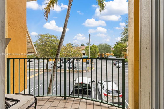 View from a balcony showing a parking area and surrounding buildings.