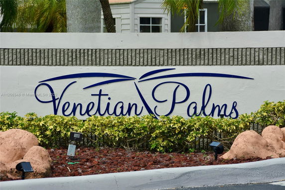 Sign with the name 'Venetian Palms' on a landscaped area.