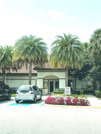 Front view of a building with a tiled roof and palm trees in front.