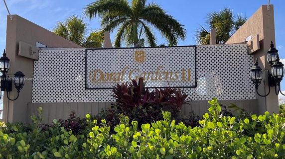 Front view of an outdoor sign with lattice background and lamps on the sides, titled 'Doral Gardens II'.