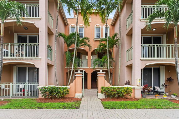 Front view of a multi-story building with balconies and arched windows.