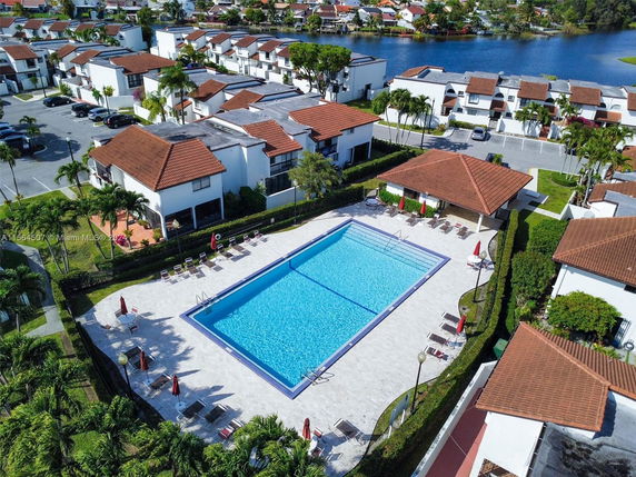 Aerial view of a swimming pool surrounded by residential buildings with brown rooftops.