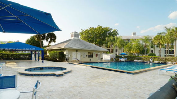 Outdoor swimming pool area with surrounding deck and a nearby pavilion.