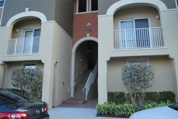 Front view of a building entrance with balconies and stairs leading up.