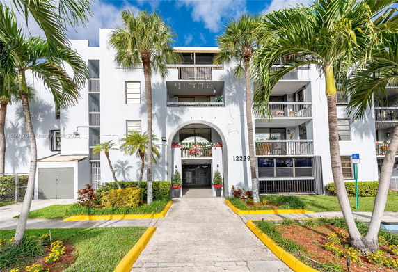 Front view of a multi-story residential building with balconies and a large entrance arch.
