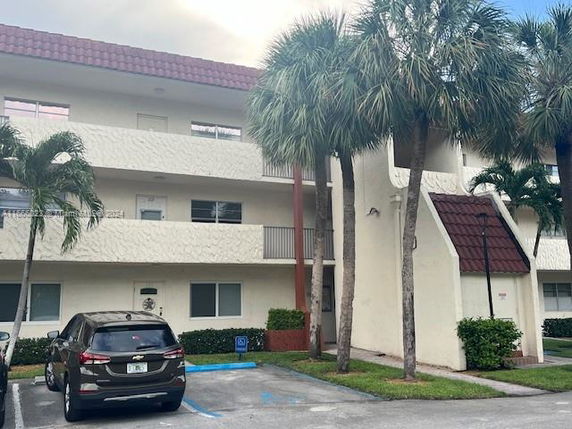 Front view of a multi-story residential building with balconies and a tiled roof.