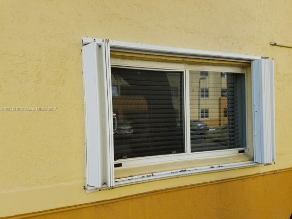 Close-up view of a yellow building window with white shutters.