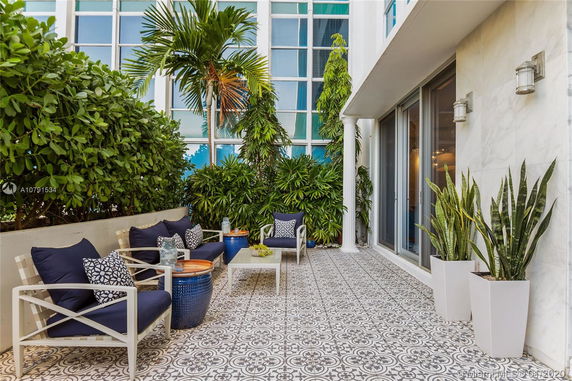 Patio area with seating and potted plants against a building facade.