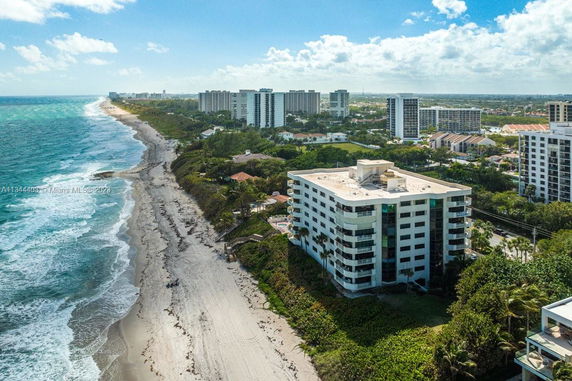 Aerial view of coastal building adjacent to the beach with ocean waves.