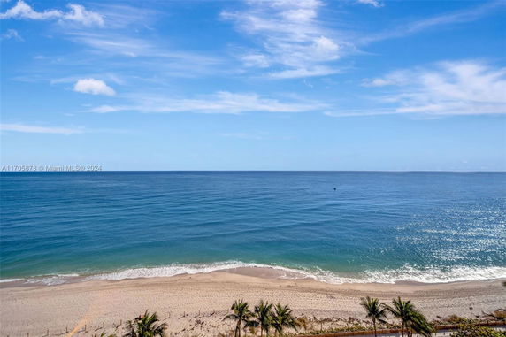 Wide angle view of a beach and ocean under a clear blue sky.