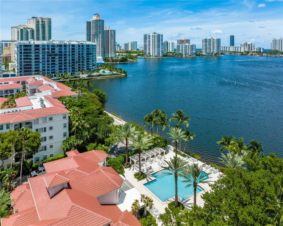 Panoramic view of a waterfront area with tall buildings and a swimming pool.