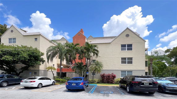Front view of a multi-story building with triangular rooflines and a central chimney.