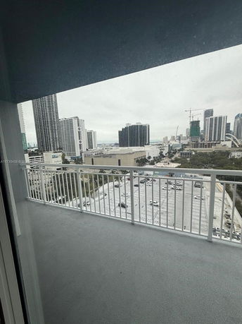Panoramic view from a balcony overlooking a cityscape with tall buildings.