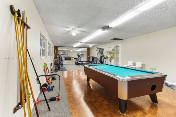 Indoor recreation area with gym equipment and a billiards table.