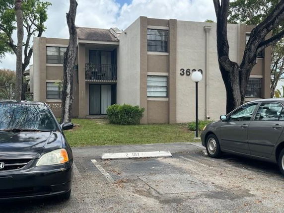 Front view of a two-story apartment building with parking spaces.