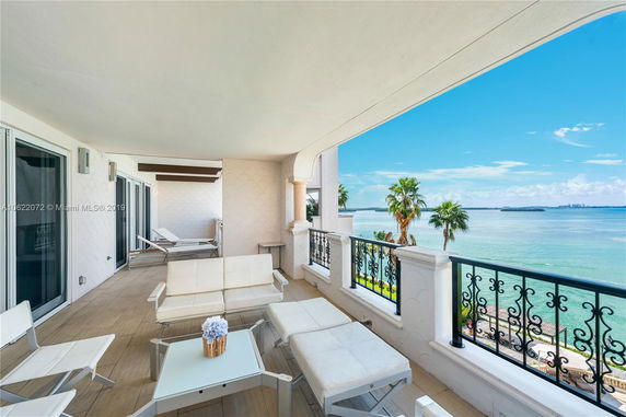 Balcony with a view of the ocean and palm trees.