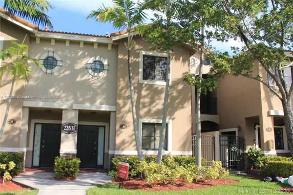 Front view of a two-story house with circular windows and a gated entrance.
