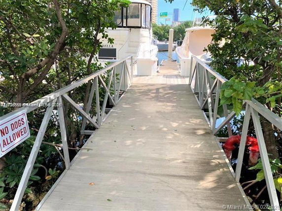 Dock with boats and a walkway surrounded by greenery.