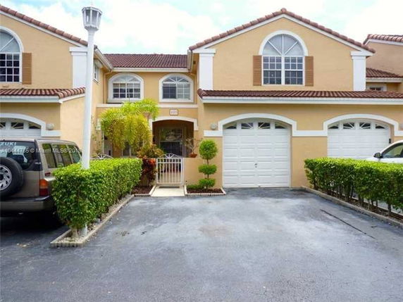 Front view of a townhouse with two garages and an arched entryway.