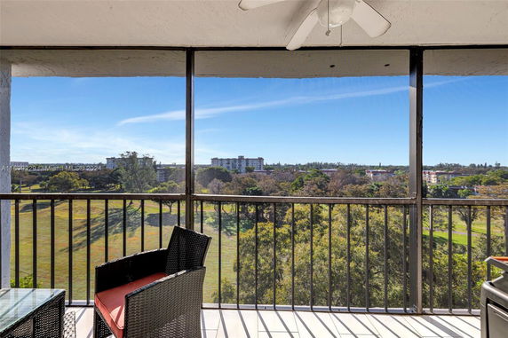 Panoramic view from a balcony overlooking a landscape with trees and distant buildings.