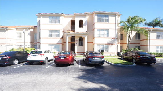 Front view of a multi-story apartment building with parking in front.