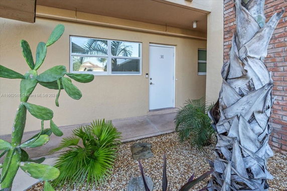 Front view of a building entrance with a white door and surrounding plants.