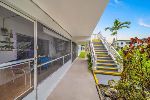 Outdoor view of building showing a walkway, staircase, and surrounding greenery.