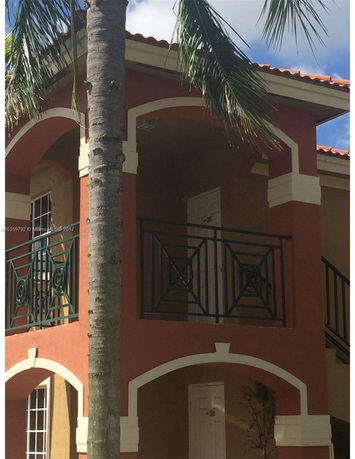 Front view of a two-story building with balconies and arched designs.