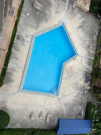 Aerial view of an outdoor swimming pool with deck chairs and a small canopy.