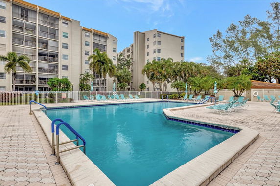 Outdoor swimming pool area with apartment buildings in the background.