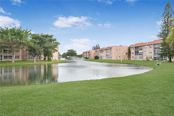 View of multi-story residential buildings near a pond with a fountain.