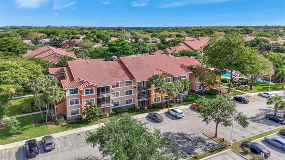 Aerial view of a residential building with a red roof and surrounding greenery.