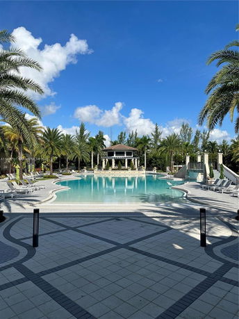 Outdoor swimming pool with lounge chairs and palm trees.
