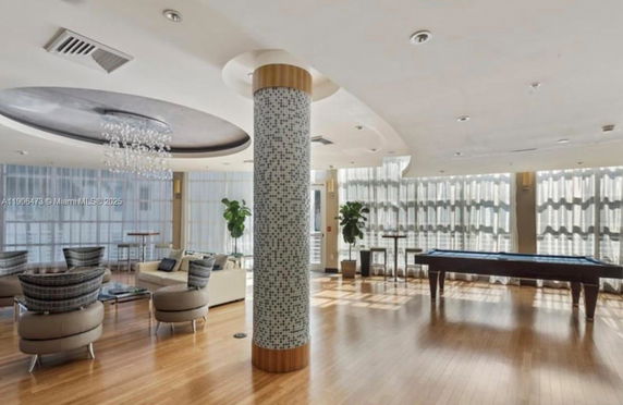 Interior view of a recreational area with seating and a pool table.