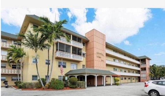 Front view of a multi-story building with balconies and a covered entrance.