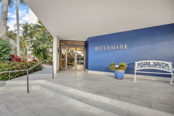 Entrance of a building named Watermark with steps, a railing, and a bench.