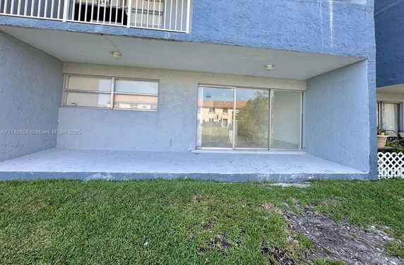 Front view of a ground-level apartment with sliding glass doors and blue exterior walls.