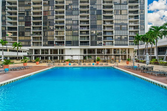Outdoor view of a swimming pool in front of a multi-story building.