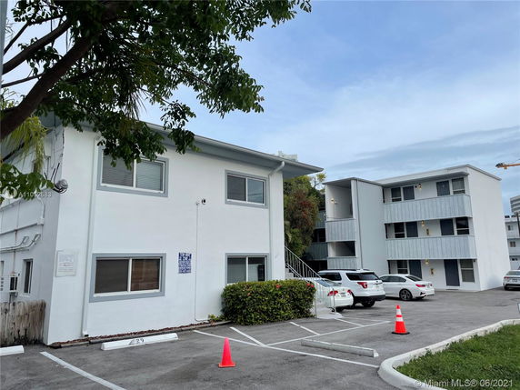 Exterior view of a two-story apartment building with adjacent outdoor parking spaces.