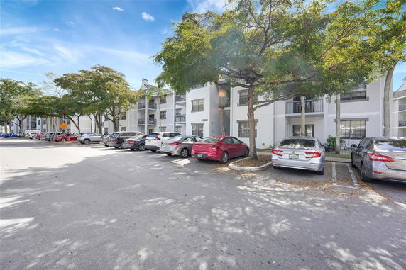 Outdoor parking area in front of a residential building with several parked cars.