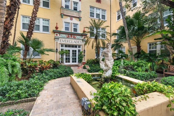 Front view of a multi-story building with an entrance labeled 'EVERGLADES' and a small fountain garden.