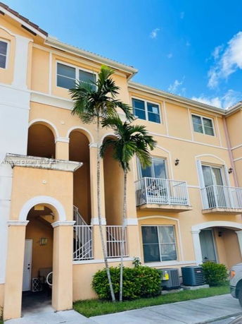 Front view of a multi-story residential building with balconies and arched entrances.