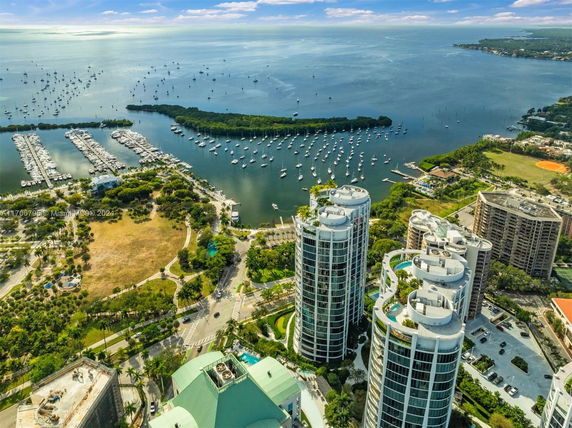 Panoramic view of tall modern buildings near a waterfront with numerous boats docked.