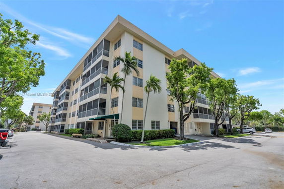 Front view of a multi-story residential building with screened balconies and beige exterior.