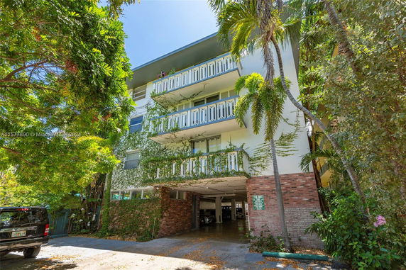 Front view of a multi-story residential building with balconies and garage entry.