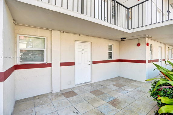 Front view of an apartment entrance with tiled flooring and a white door.