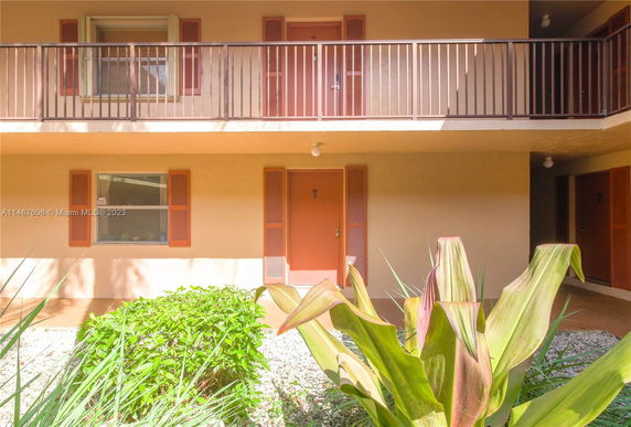 Front view of a multi-story building with balconies and plants in the foreground.
