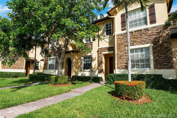 Front view of a two-story townhouse with stone accents and a landscaped walkway.
