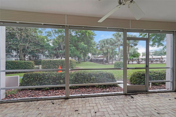 View from a screened patio with greenery and a pool area visible outside.
