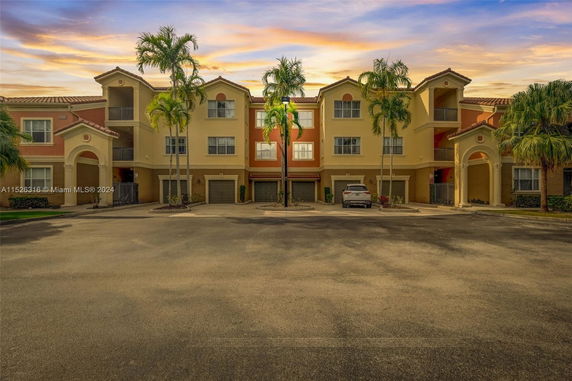 Front view of a three-story residential building with a symmetrical design and garages on the ground floor.